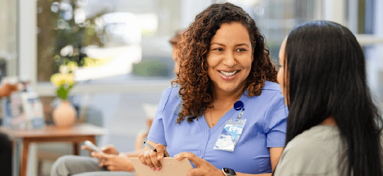 woman with work badge smiling at another person