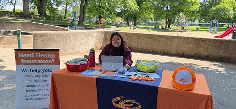 woman sits at outdoor information table