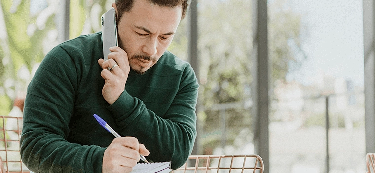 Man holding phone and pen